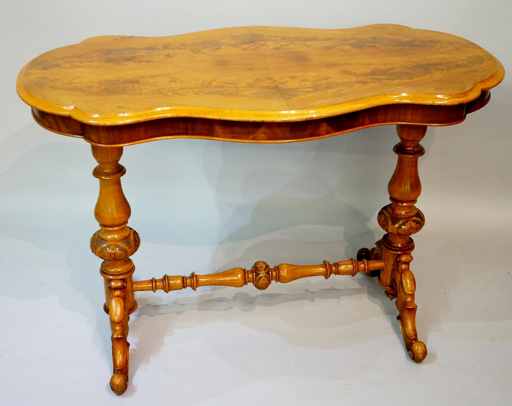 A Victorian serpentine-shaped centre table the butterfly veneered top above a shallow frieze on