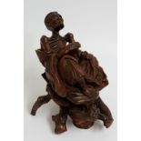 A Chinese root wood figure, finely carved as an emaciated man holding a bowl on a root wood base,