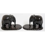 A pair of ebonised hardwood carved elephants on gadrooned lignum rounded rectangular bases,