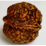 A Japanese walnut shell profusely carved with figures, flower heads and leafage, 4cm high,