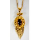 A Victorian gold pendant the stepped oval frame bead and leaf clasped with central oval garnet
