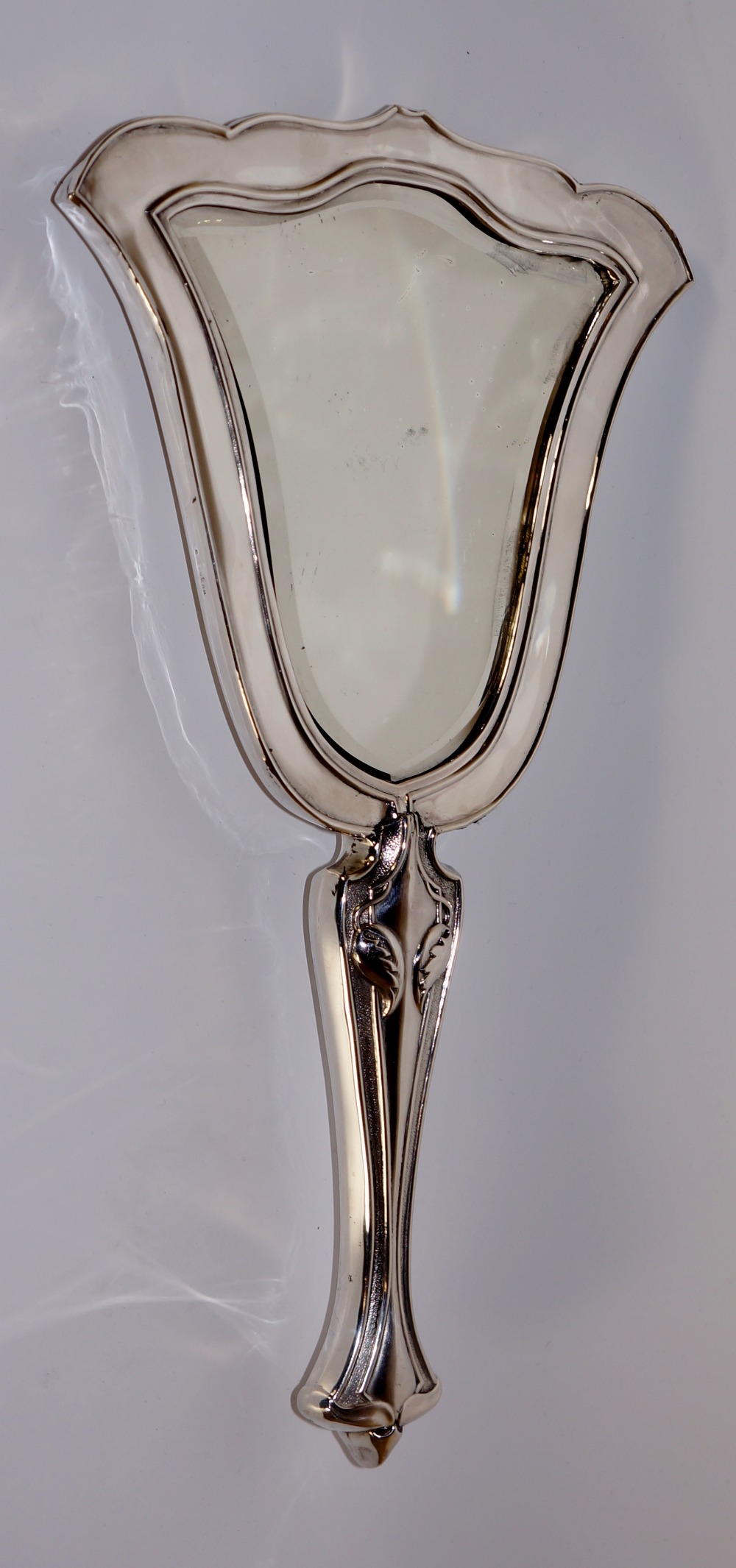 An Edward VII silver hand mirror in Art Nouveau style embossed with flower heads and trailing