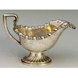 A late Victorian cream jug, boat shaped, with stylised foliate rim and C-scroll handle,