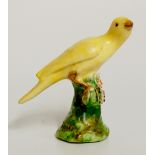 A Derby bird perched on a floral encrusted green branch and base,