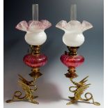 A pair of oil lamps, each brass base in the form of a dragon breathing fire,