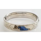 A Continental silver coloured metal bangle with wriggle work borders the centre inlaid in enamel