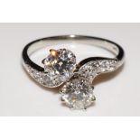 A platinum diamond cross-over ring with pair of circular cut claw set brilliants,