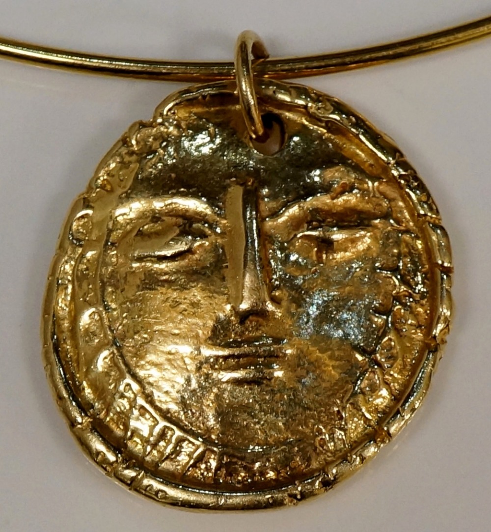 Picasso - a 14ct pendant by Madoura, the shaped circular gold nugget cast with a stylised face,