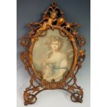 A finely carved pierced oval frame with cherub top holding a vacant cartouche the scrolling frame