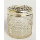 An Edward VII silver topped dressing table jar the slightly domed cover foliate scroll embossed,