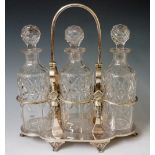 An Edwardian three bottle cruet frame with swing handle, the frame cast with bearded masks,