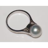 A pearl ring, the pearl seated in a circular crown with rising shoulders,
