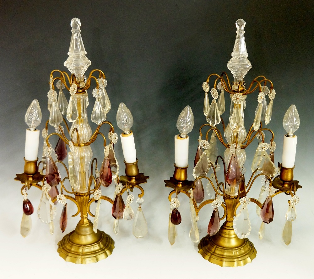 A pair of brass two branch candelabrum with clear glass columns with three scrolling tiers each