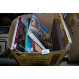 A box of books, coffee table books inclu