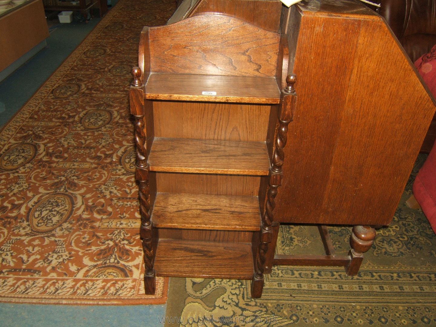 A narrow 1940's Oak open Bookcase, having gallery top, four shelves and having on barley twist