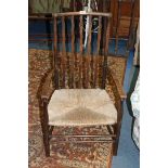 An arts and crafts Beech Elbow Chair, wavy lath back, plain arms, rush seat, standing on turned