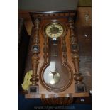 A Wall Clock in ornate wooden case, Roman numerals and fleur-de-lys pattern to face