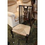 An arts and crafts stained Beech nursing Chair with pierced fret cut splat, flanked by spindle