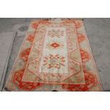 A cream and orange ground woven woollen Rug with fringe borders and geometrical symmetric patterns