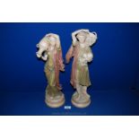 A pair of Royal Dux Bohemian figures of a Boy carrying a basket of fruit and girl carrying two