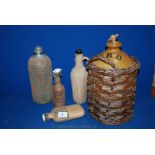 A mesh cased Soda Syphon -  top missing and three wicker cased bottles and a Stoneware Bottle in a