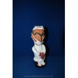 A Chelsea pottery figure of a Surgeon, 22 cms high in a white apron, mask and purple gloves,