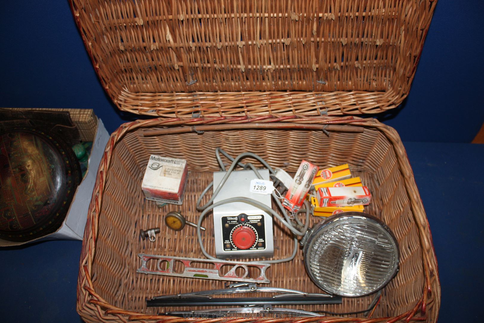 A wicker Picnic Basket containing Lucas headlight, spark plugs, small spirit level, petrol cap,