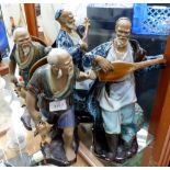 Two pairs of unmarked ceramic figures of Japanese men playing musical instruments and carrying fish