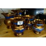 Five graduated vintage copper lustre jugs wutg blue foliate borders