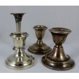 Three silver and white metal candle holders and a posy vase