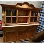 Pine dresser on bun feet with three drawers over two cupboards, glazed top on pillar supports.189