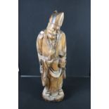 CARVED WOOD FIGURE - A Chinese hardwood carving of a Chinese man, possibly a priest, damage to face,