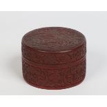 A Chinese cinnabar lacquer circular box and cover. The lid is carved in relief to depict a seated