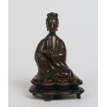A Chinese patinated bronze figure of Guanyin seated. Raised on a carved hardwood plinth, 18cm.
