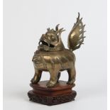 An Antique Chinese bronze temple censor. Formed as a mythical beast raised on a carved hardwood