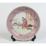 A Chinese famille rose dish. Painted with a wide stylized border framing an outdoor scene with a