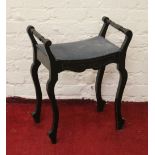 A Victorian ebonized piano stool with under seat storage and raised on cabriole supports.