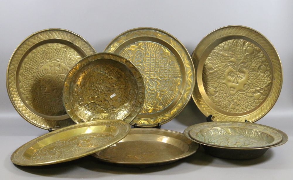 A collection of C19th brass chargers and dishes each with embossed decoration.