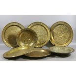 A collection of C19th brass chargers and dishes each with embossed decoration.