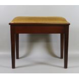 A mahogany piano stool with under seat storage and raised on tapering supports.