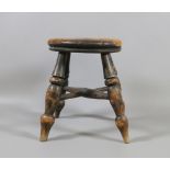 A small antique kitchen stool raised on turned supports.