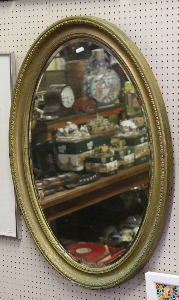 An oval gilt framed bevel edge wall mirror.