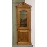 A large carved pine corner unit with glazed top section over cupboard base.