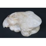 A Chinese carved hardstone model of a toad raised on a stylized leaf. Pale jade in colour and with