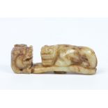 A Chinese carved hardstone belt buckle of jade colour. Formed as two mythical beasts, 9.5cm.