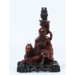 A Chinese early twentieth century carved hardwood figural tablelamp on stand. Formed as a seated