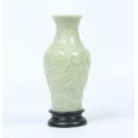 A Chinese Peking glass baluster vase on hardwood plinth. Celadon ground and decorated in relief with