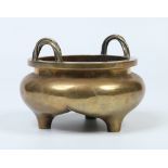 A Chinese bronze censor of circular form and with a pair of ropetwist handles. Raised on three