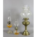 A brass based oil lamp with etched glass shade along with two pressed glass examples.