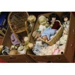 Two boxes of various collectors dolls along with a miniature basket ware chair.